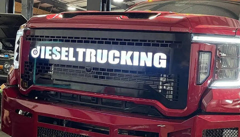 Custom grille for GMC 2500-3500 with LED lights and backglow text, made from 304 stainless steel, installed on a red truck.