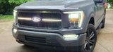 Front view of a Ford truck with illuminated headlights on a driveway.