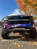 Custom LED grille insert for 2016-2018 Chevy 1500 shown with a gloss black powdercoat and multicolor LED backglow, featuring the text ' GALAXY ' customized on the center bar.